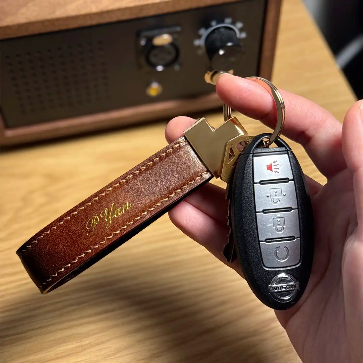 Hand holding a car key with a brown leather keychain