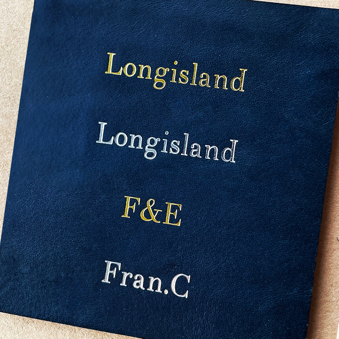 Examples of personalized gold foil stamping on navy blue Italian leather for custom orders.