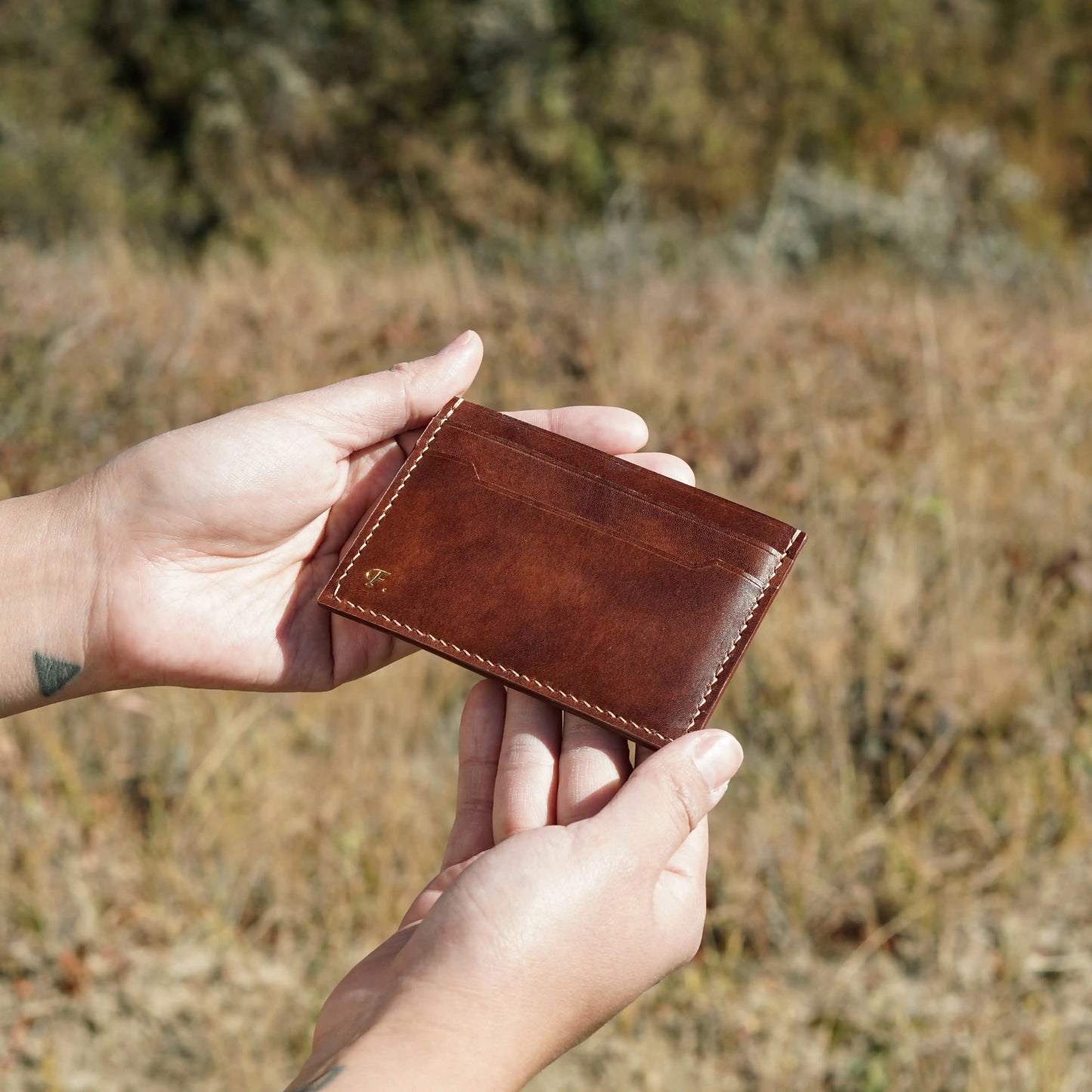 Handcrafted Italian leather wallet held in hands showing natural texture and finish.