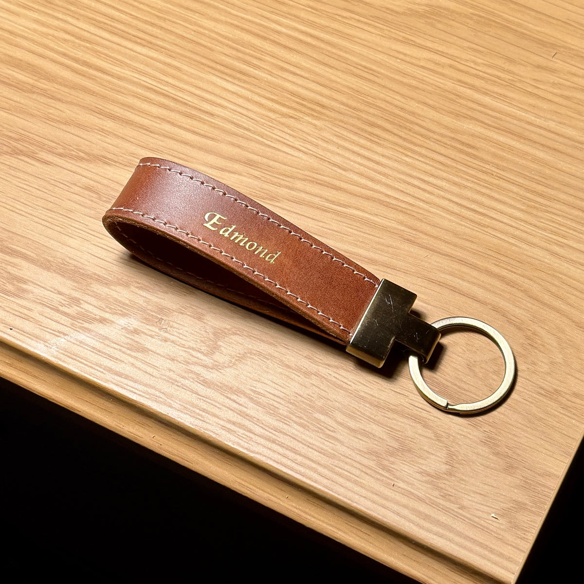 LOOP personalized leather loop keychain with metal split ring on a wooden surface