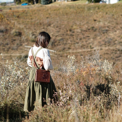 Rear view of a model wearing the Maple crossbody leather bag in a scenic outdoor setting.