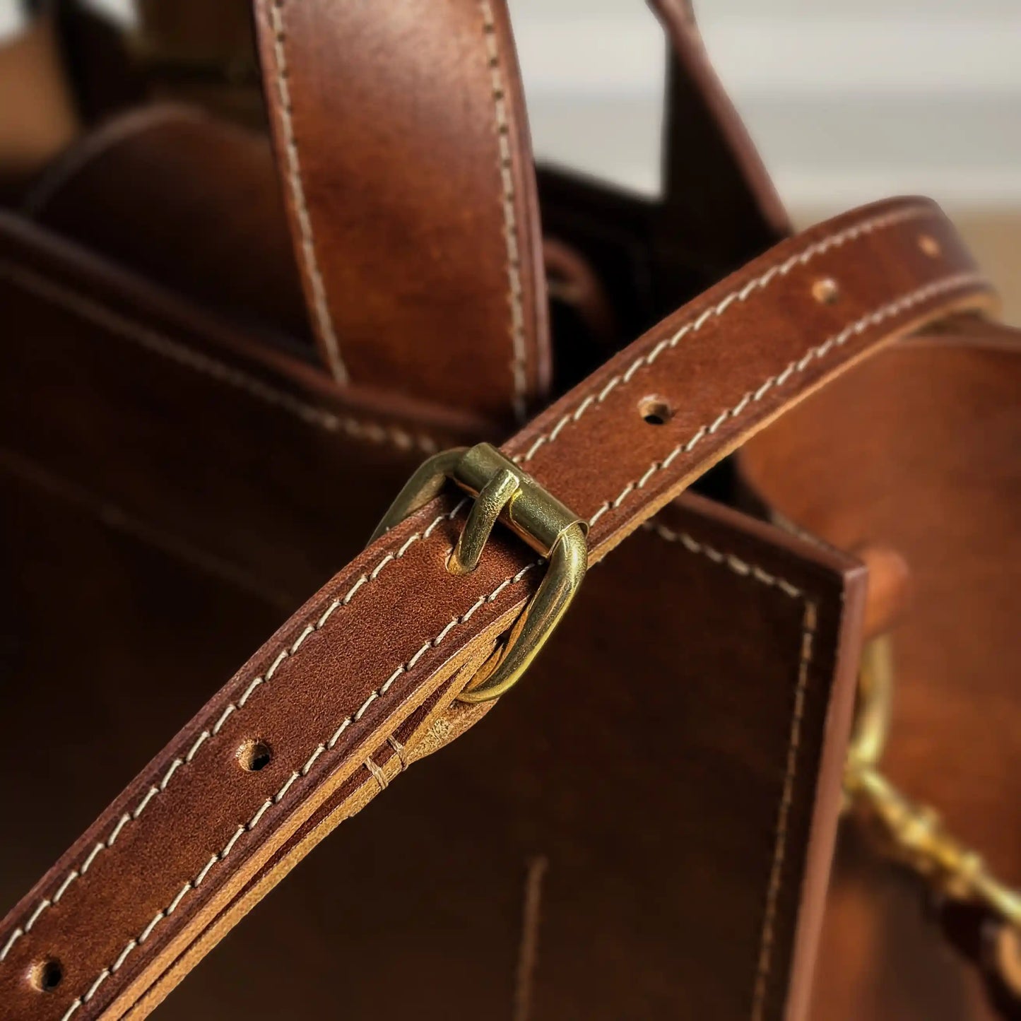 Detail shot of the durable golden hardware and shoulder strap attachment on the Maple bag