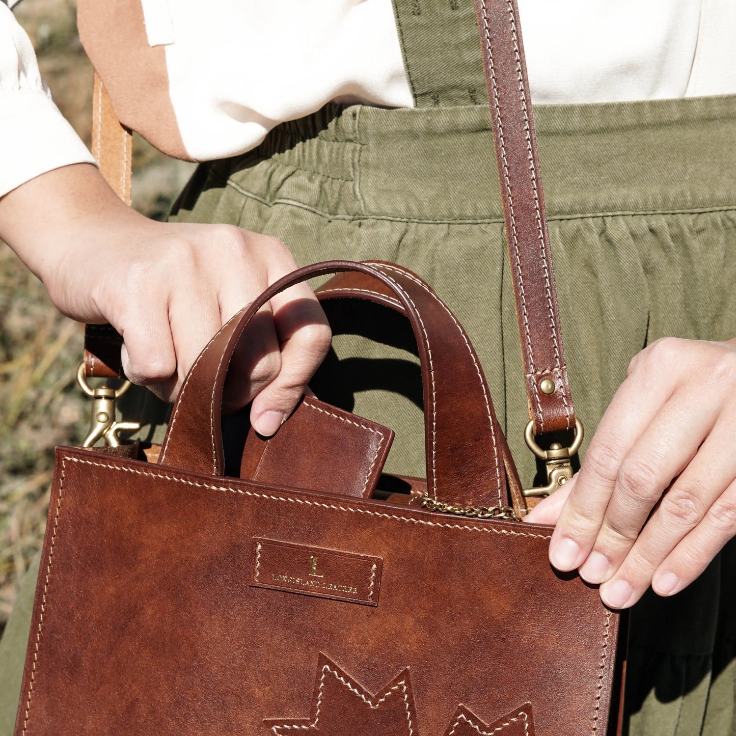 Opening the Maple leather handbag to show a wallet inside, demonstrating its roomy interior.