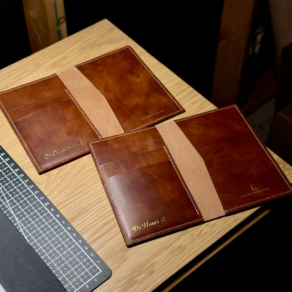 Two open handmade leather passport covers showing card slots and passport sleeves